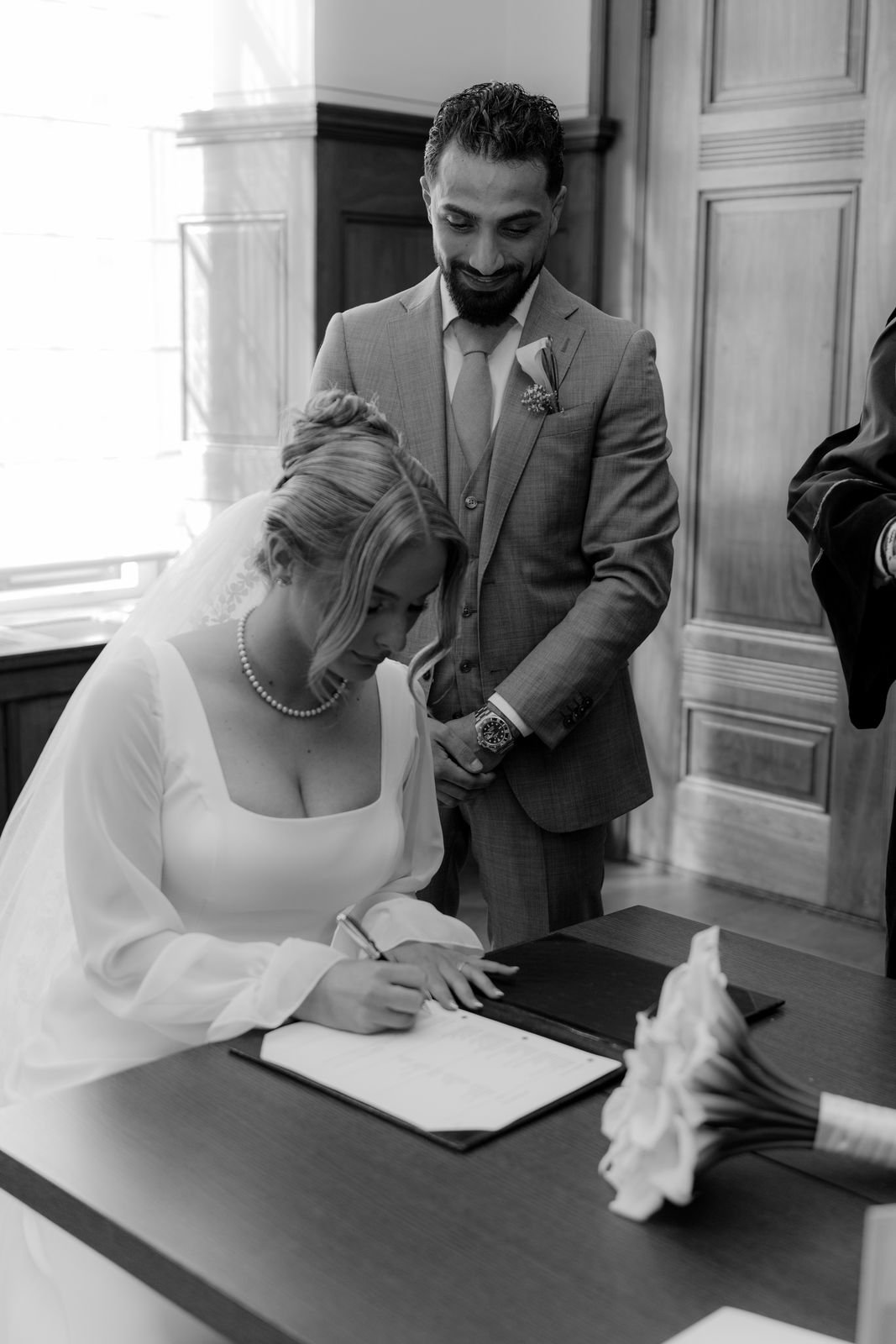 Bruid en bruidegom zetten hun handtekening aan een tafel tijdens de ceremonie