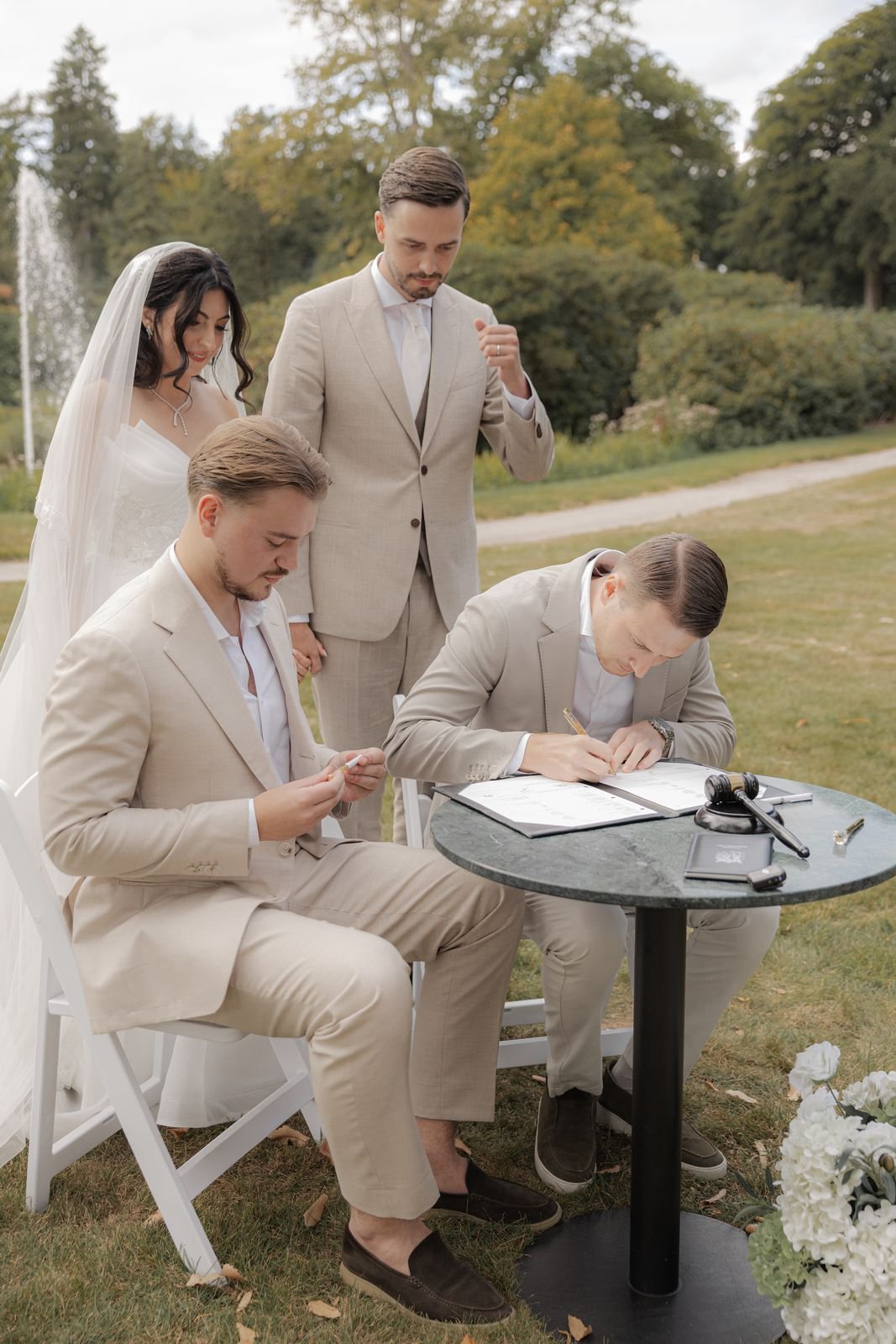 Bruid en bruidegom staan bij een tafel terwijl er na de ceremonie getekend wordt
