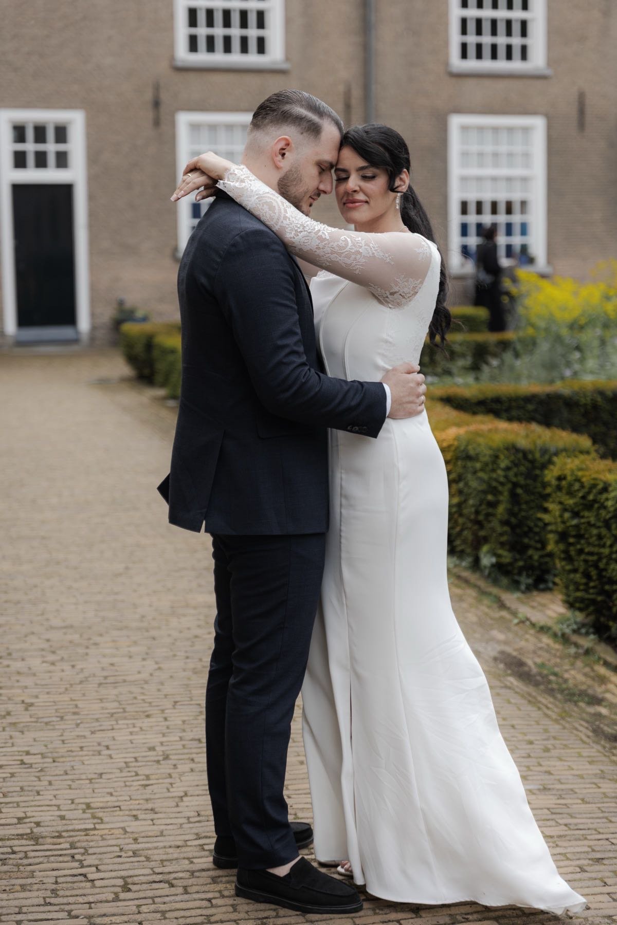 Bruidspaar omhelst elkaar op een binnenplaats