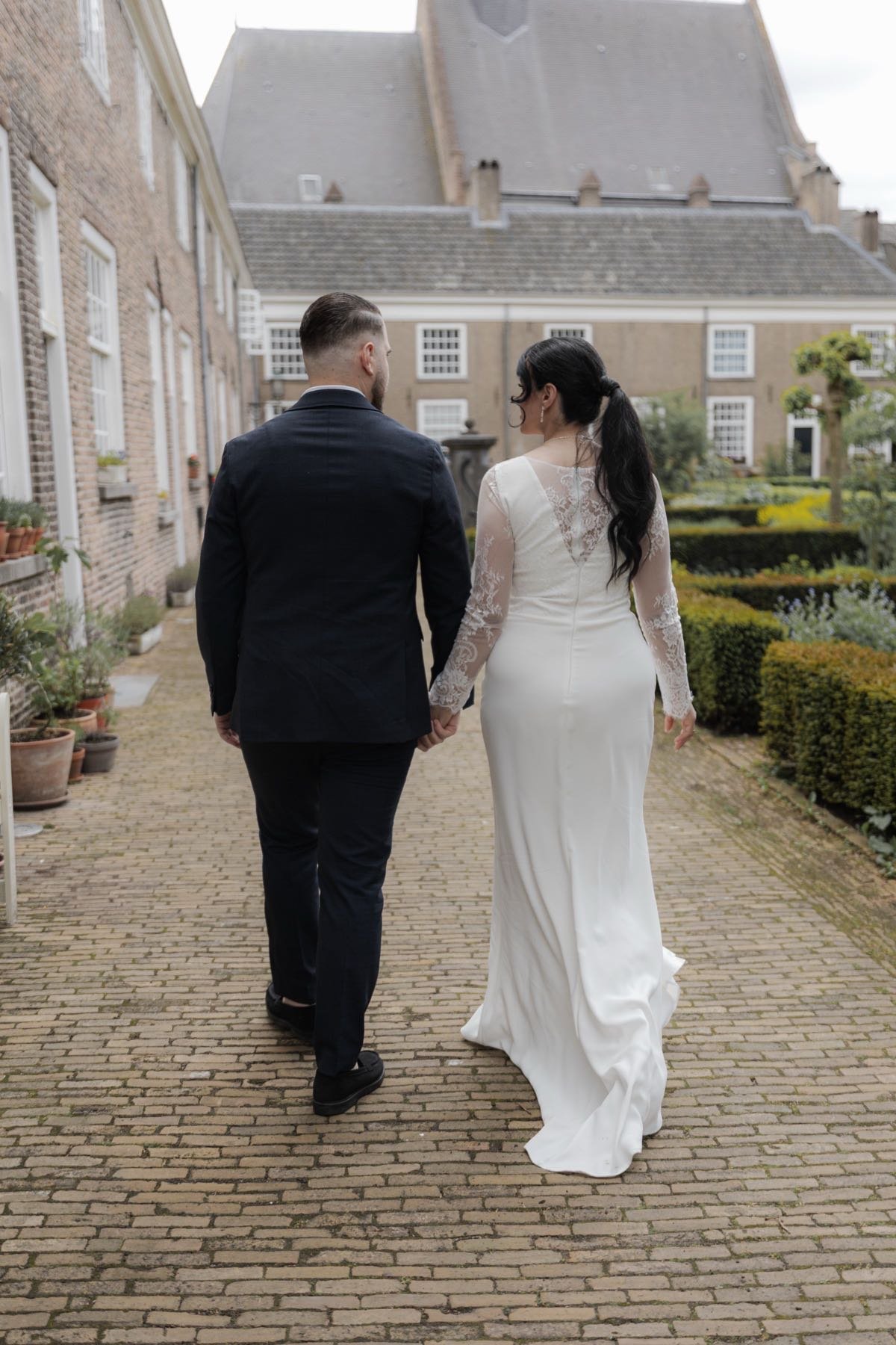 Bruidspaar loopt hand in hand over een binnenplaats