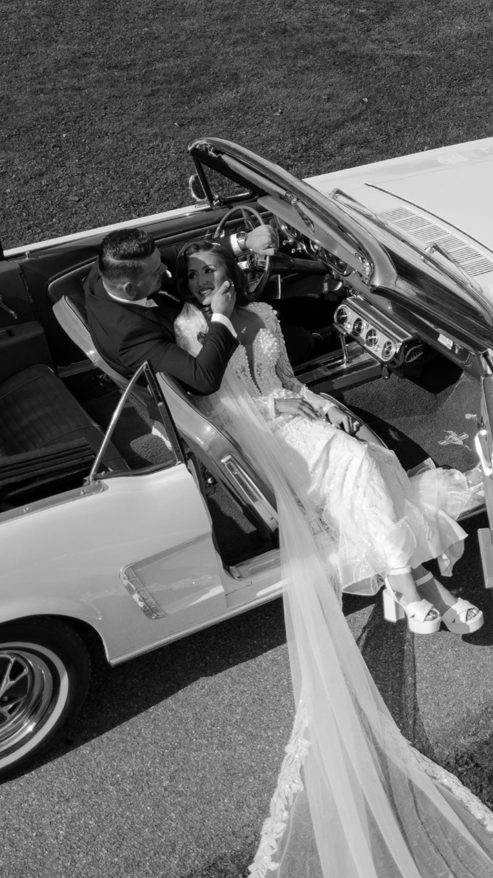 Bruidspaar in een witte cabrio, in zwart-wit